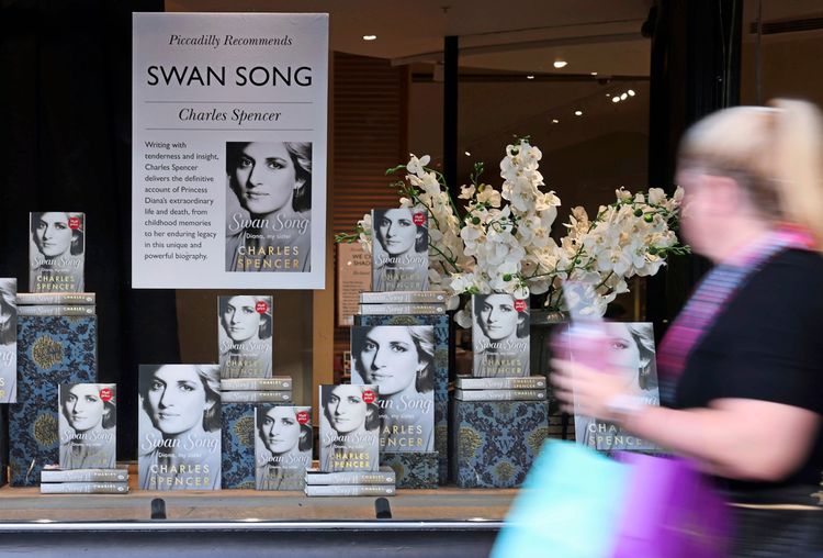 Eine Frau läuft an einem Schaufenster der Buchhandlung Waterstones in London vorbei, in dem zahlreiche Exemplare des Buches „Swan Song: Diana, My Sister“ von Charles Spencer, dem Bruder der verstorbenen Prinzessin Diana, ausgestellt sind. Das Schaufenster ist zudem mit weißen Blumen dekoriert.