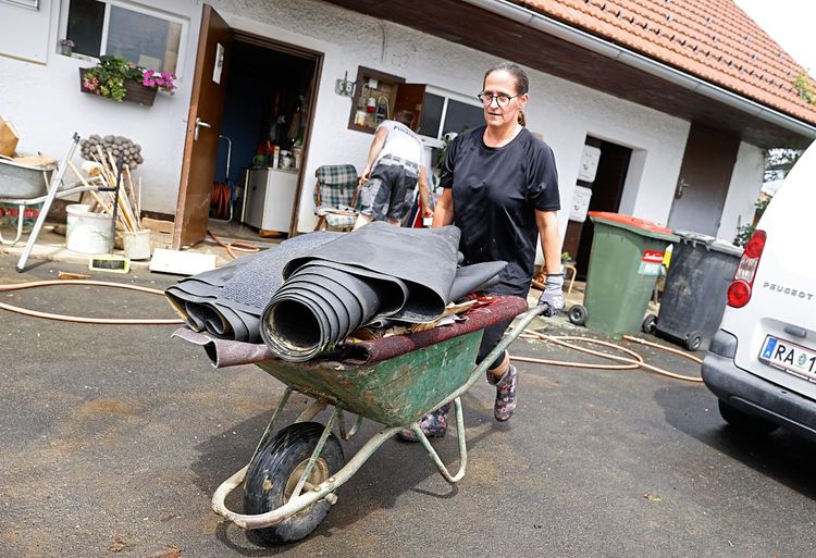 Im Süden Österreichs kam es aufgrund der anhaltenden Regenfälle zu Überflutungen und Hangrutschungen. Im Bild ist eine Frau zu sehen mit einer Scheibtruhe - sie mistet die von der Überschwemmung ihres Hauses betroffenen Gegenstände aus.