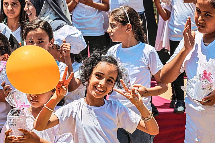 Ein palästinensisches Mädchen mit einem orangen Luftballon lächelt in die Kamera.
