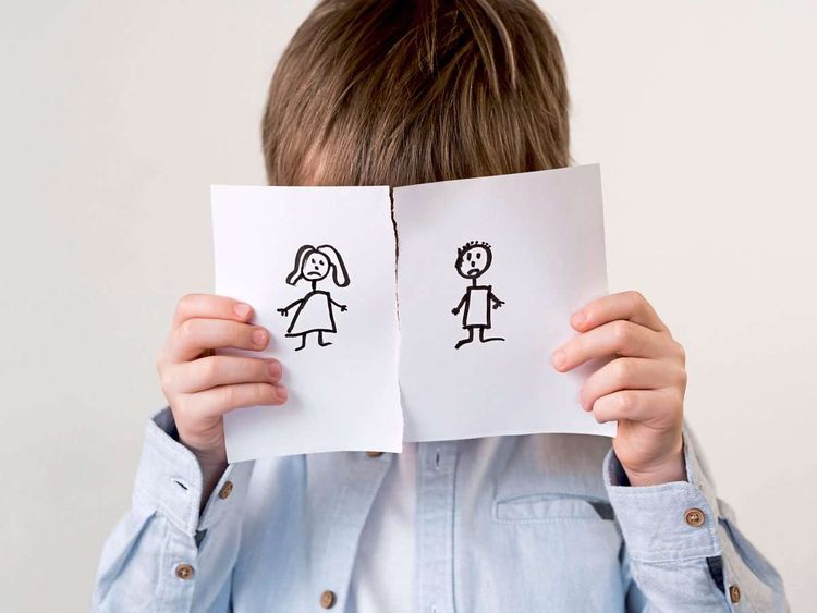 Kind hält zwei Blätter vor sein Gesicht, auf jeweils einem Blatt ist ein Elternteil abgebildet