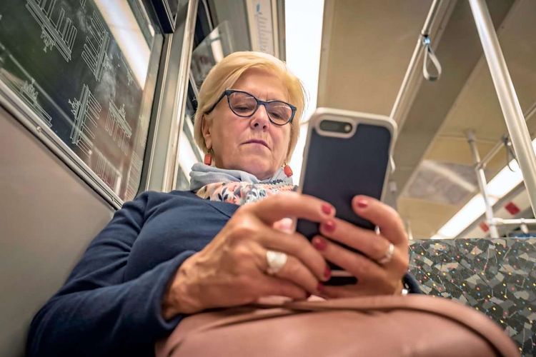 Eine Frau hält ein Smartphone in der U-Bahn in Händen