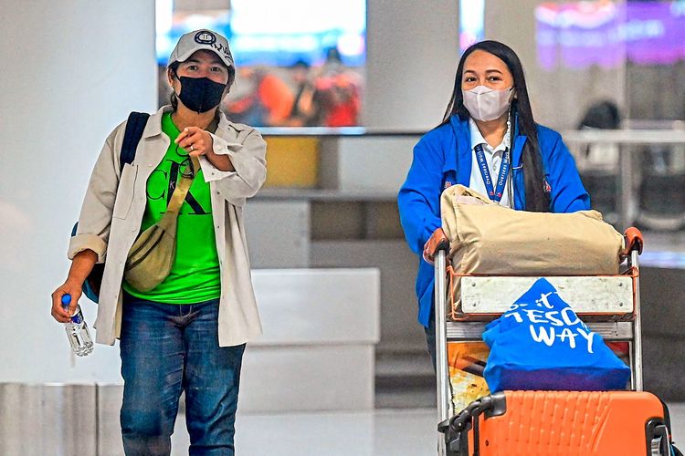 Zwei Philippinerinnen mit Gepäckwagen am Flughafen