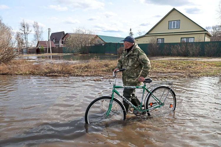 Mann wattet durch das Wasser mit einem Fahrrad.
