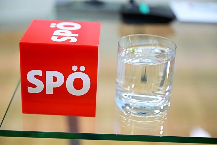 Rotes Schild auf dem SPÖ steht neben einem Glas Wasser