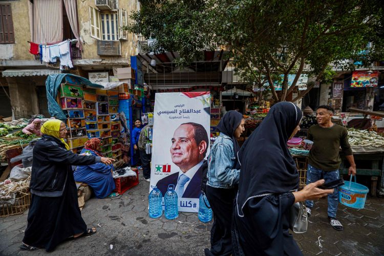Ein Wahlplakat mit Abdelfattah Al-Sisi auf einem Markt in Kairo, rundherum Passantinnen.