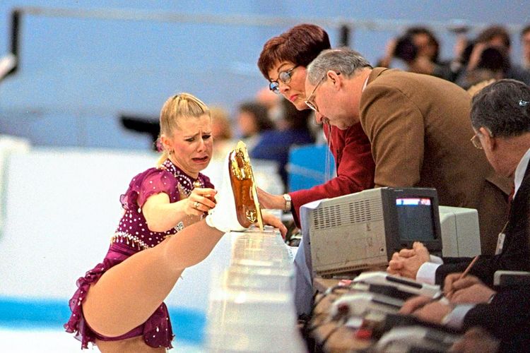 Tonya Harding veranschaulicht den Juror:innen bei den Olympischen Winterspielen 1994 ihre Probleme mit den Schnürsenkeln.