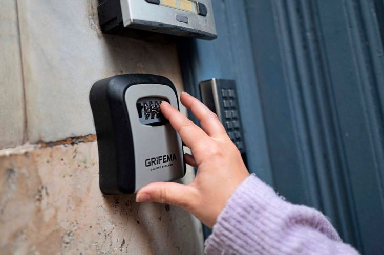 Eine Person gibt den Code in eine Schlüsselsafe-Box an einem Eingang ein.