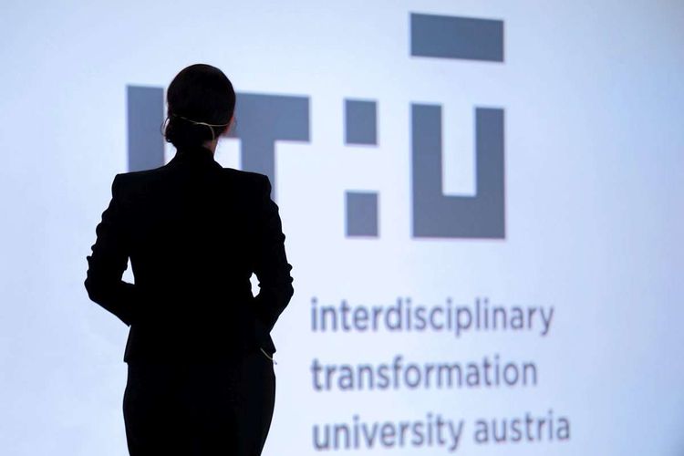 Schattenriss der Gründungspräsidentin der Digital-Uni Linz, Stefanie Lindstaedt, vor dem Logo der IT:U.