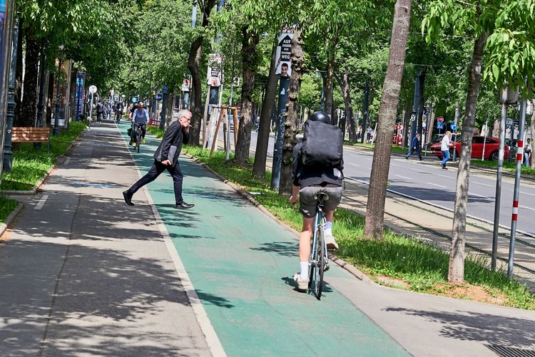 Ein Mann läuft knapp vor einem Fahrrad über den Radweg