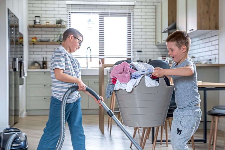 Zwei Burschen helfen zuhause mit, einer saugt und einer macht die Wäsche