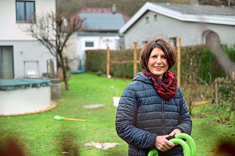 Sophie Plöchl, Parkinson-Betroffene, steht in einem Garten und lächelt
