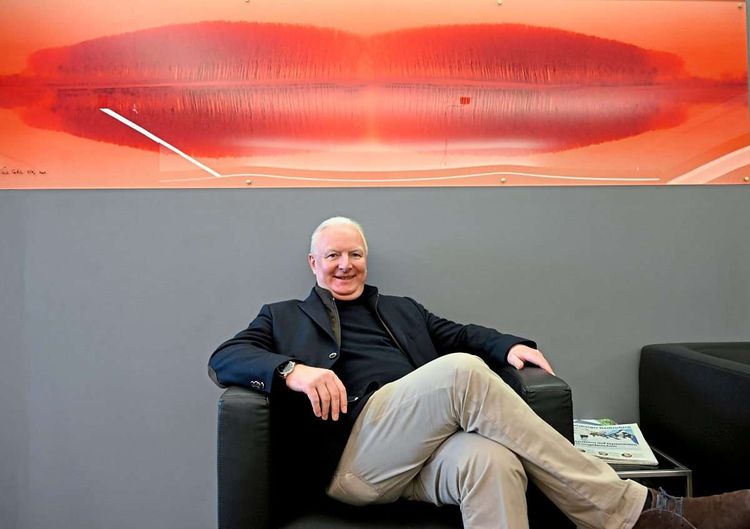 ÖVP-Bürgermeisterkandidat Florian Kreibich sitzt vor einem Bild.