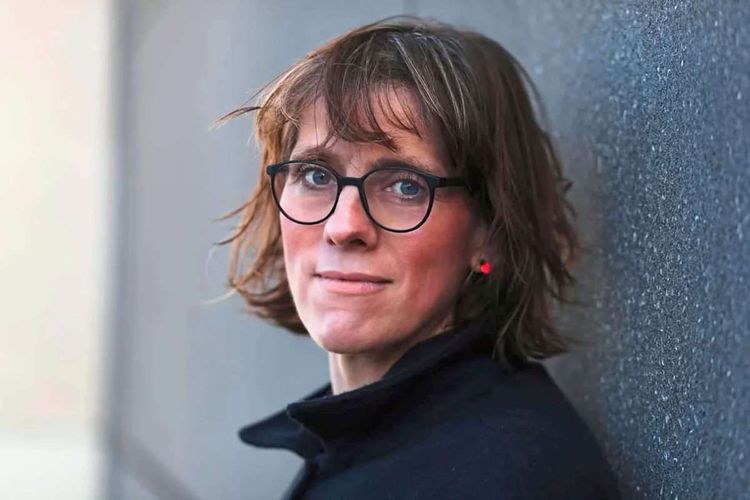 Porträtfoto der Autorin und Journalistin Katrin Seyfert, sie steht vor einer grauen Wand 