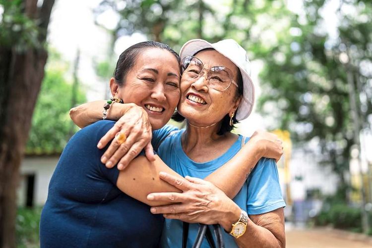 Asiatische Freundinnen umarmen sich glücklich in einem Park