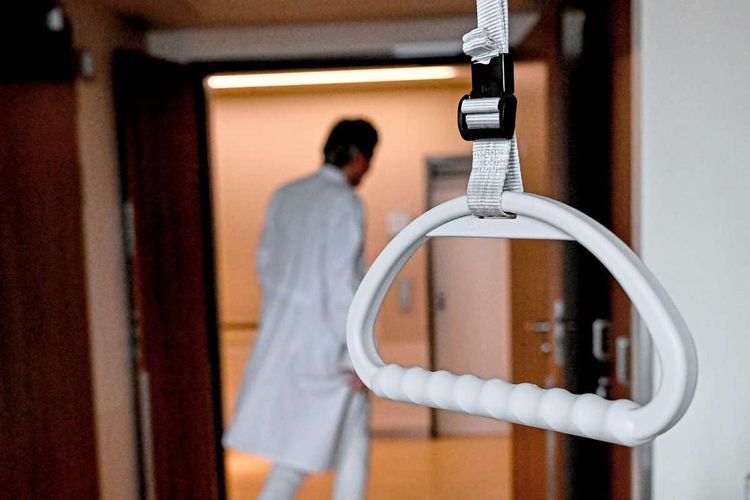 Haltegriff eines Krankenbettes vor einem Arzt, der gerade ein Krankenzimmer verlässt
