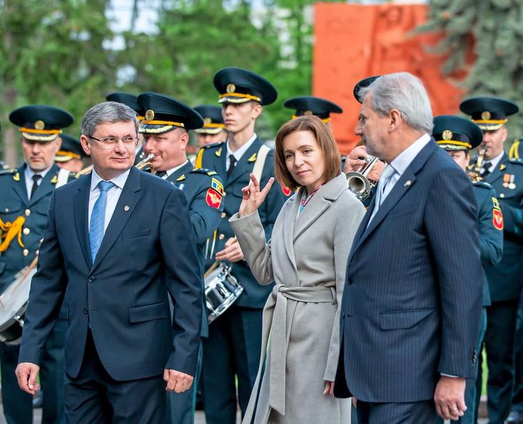 Die moldawische Präsidentin Maia Sandu steht zwischen EU-Kommissar Johannes Hahn (rechts) und dem Präsidenten des moldawischen Parlaments, Igor Grosu (links). Im Hintergrund spielt eine Militärkapelle.