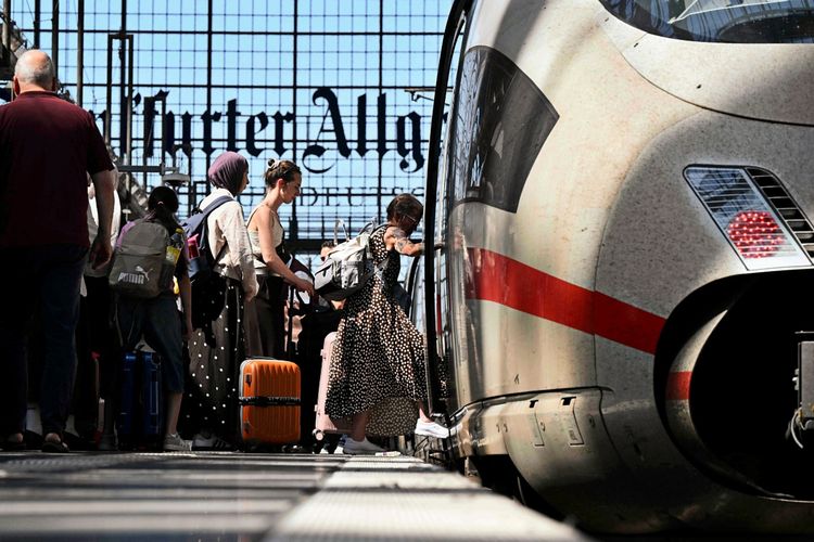 Menschen steigen in einen ICE-Zug der Deutschen Bahn am Frankfurter Hauptbahnhof ein. Im Hintergrund sind das Bahnhofsgebäude und das Schild 