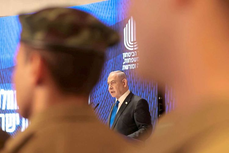 Benjamin Netanjahu spricht im Hintergrund, im Vordergrund Soldaten