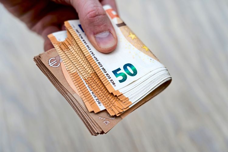 Eine Hand hält ein Bündel aus 50-Euro-Geldscheinen.