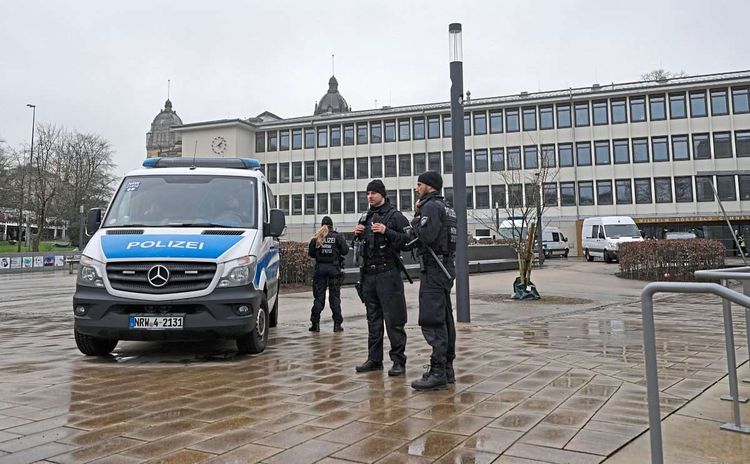 Polizeiauto und Polizisten vor Schule.