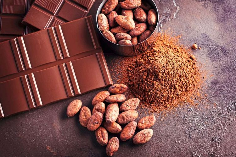 Ansicht von oben auf Schokoladentafeln, Kakaobohnen und Kakaopulver – ein braunlastiges Bild.