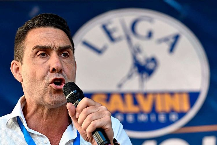 Roberto Vannacci mit einem Mikrofon in der Hand vor dem Logo der Lega.