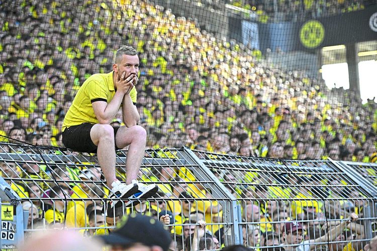 Ein Dortmund-Fan sitzt auf dem Zaun.