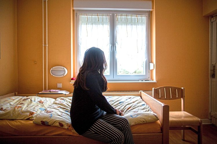 Eine Frau sitzt auf einem Bett in einem Frauenhaus.