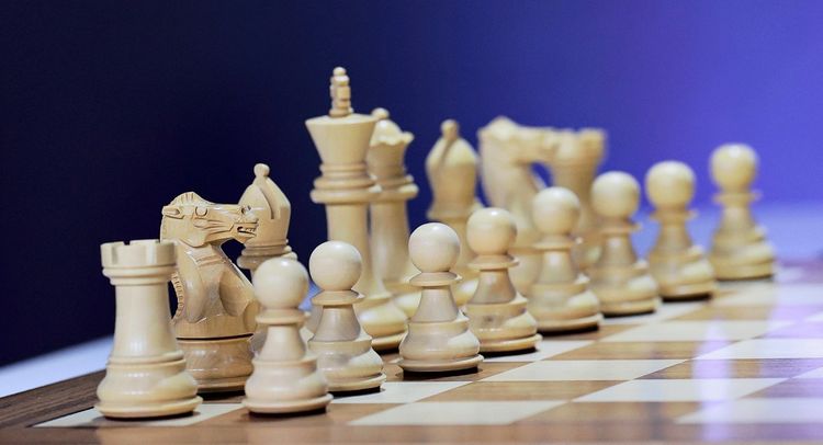 Offizielle weiße Schachfiguren auf einem Schachbrett, aufgenommen vor Beginn des ersten Wettkampftages des Grand Chess Tour 2026 - „Super Chess Classic Romania“ - im Nationalbankpalast von Rumänien in Bukarest, 14. Mai 2026. Die Figuren sind in einer geordneten Reihe angeordnet, erkennbar vor einem verschwommenen Hintergrund.