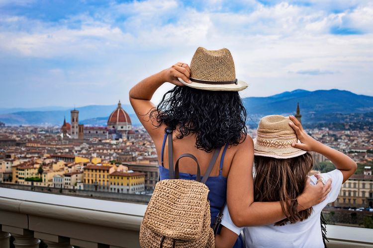 Zwei Personen mit Strohhüten schauen auf die Aussicht über Florenz, Italien, mit der markanten Kuppel des Doms Santa Maria del Fiore im Hintergrund.
