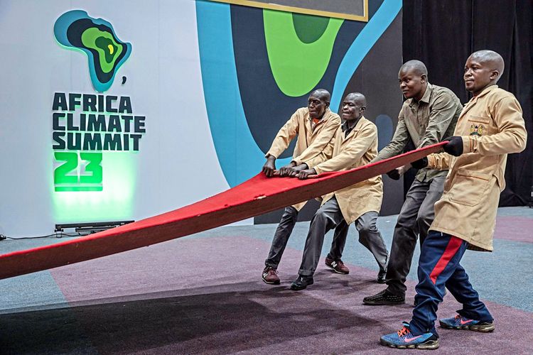 Arbeiter legen auf der Bühne des Klimagipfels den roten Teppich aus