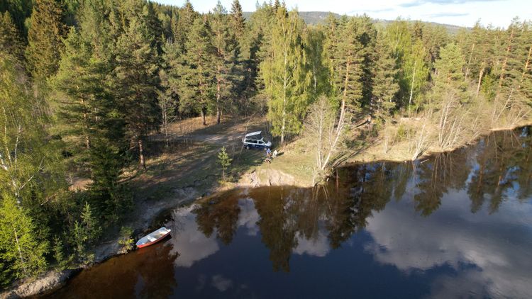Ein Camper am Waldrand am Ufer eines Sees