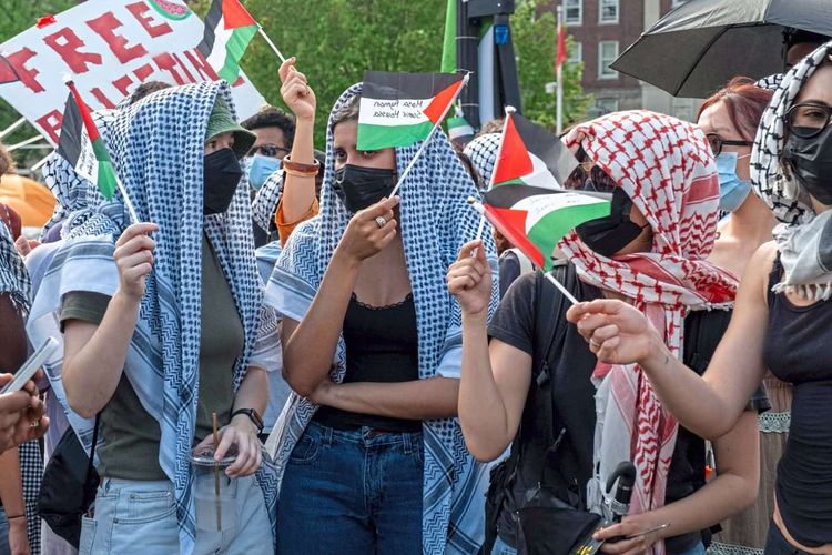 Demonstrierende schwenken palästinensische Flaggen.