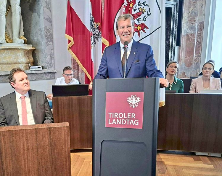 Ein Mann steht an einem Rednerpult mit der Aufschrift 