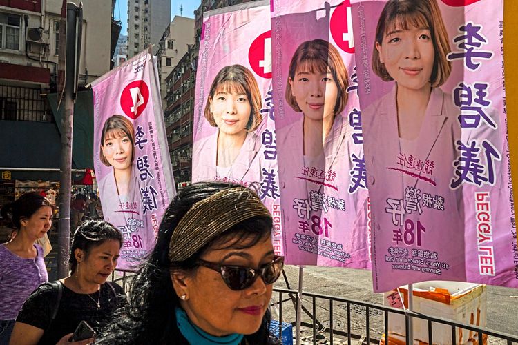 Fußgänger gehen an Plakat mit Kandidatin für Bezirksrat vor Hongkonger Wahlen vorbei