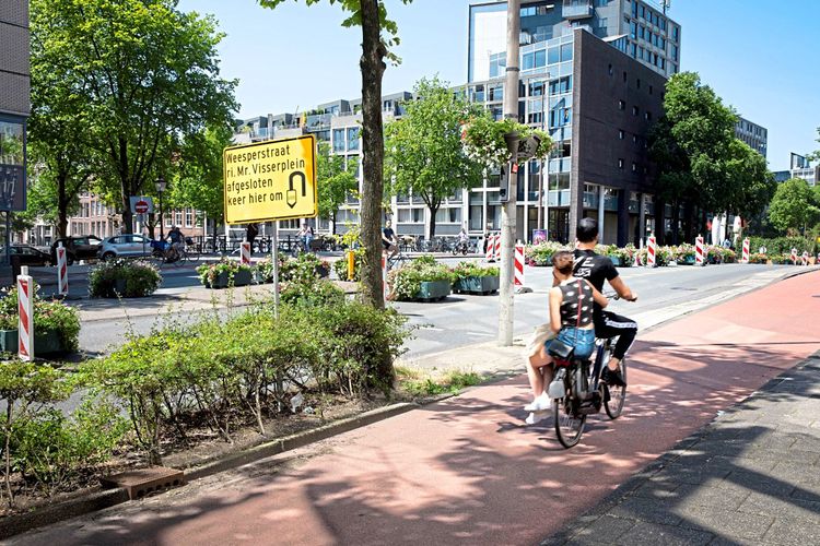 Zwei Menschen fahren auf dem Rad über eine leere Straße