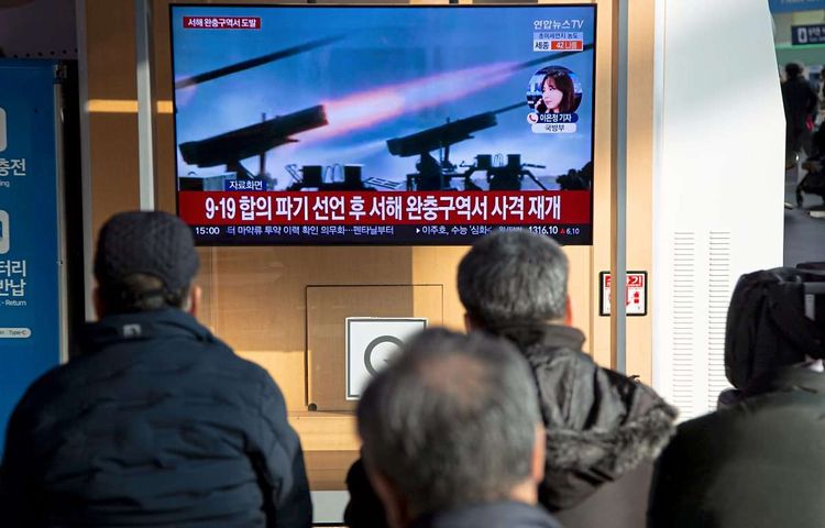Menschen in Seoul vor einem TV-Bildschirm. Auf diesem sind Raketenwerfer zu sehen.