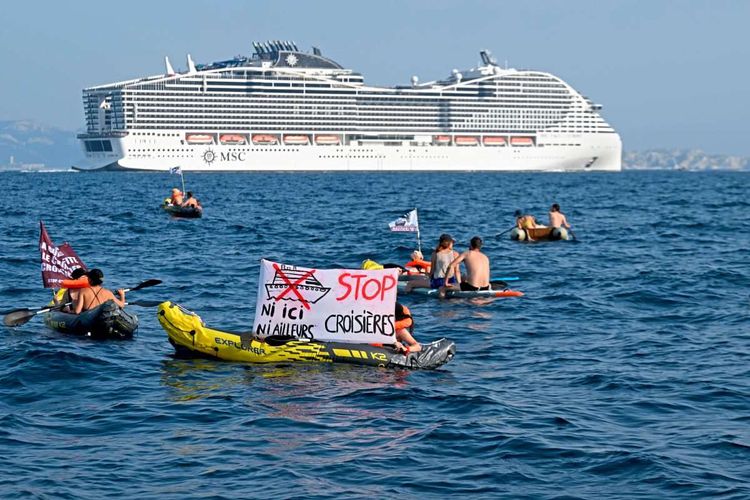 MSC World Europa im Meer, davor aktivisten auf Schlauchbooten, die Transparente hochhalten