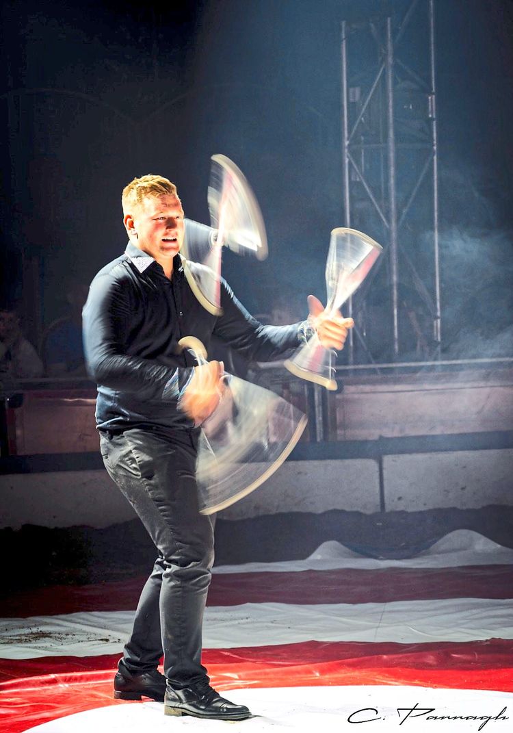Marvin Spindler vom Zirkus Safari steht in der Manege und jongliert mit Kegeln.