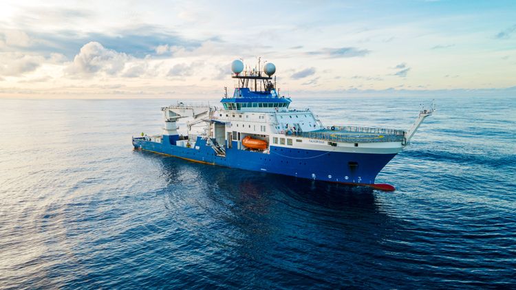 Das blau-weiß lackierte Forschungsschiff Falkor (too) auf dem Ozean.