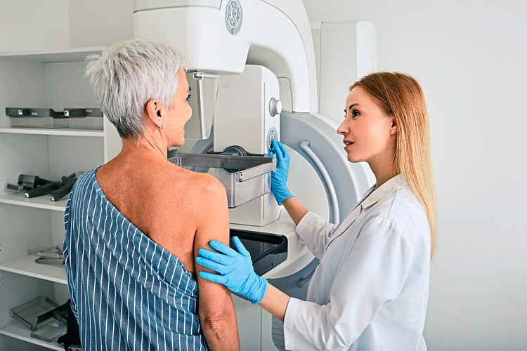 Eine Frau steht vor dem Mammographiegerät. Die Ärztin gibt ihr Anweisungen.