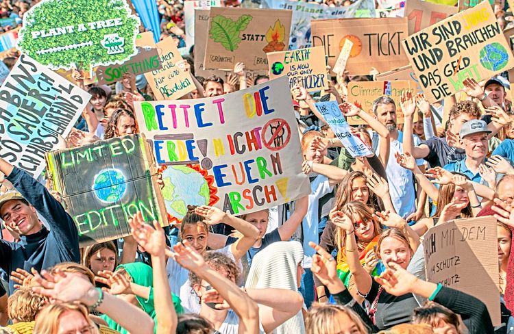 Eine Menschenmenge mit bunten Plakaten auf einer Klimademo