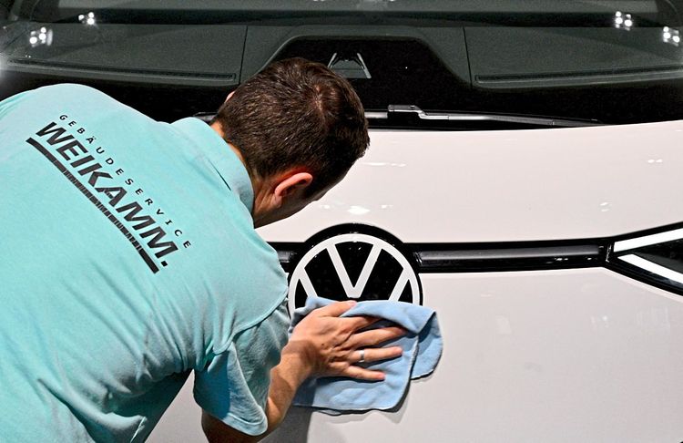 Ein Arbeiter reinigt ein VW-Logo.