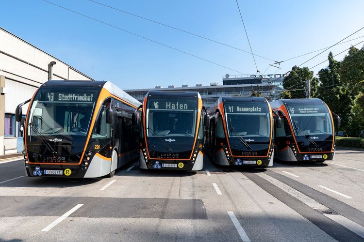 Vier Stadtbusse auf asphaltierter Straße