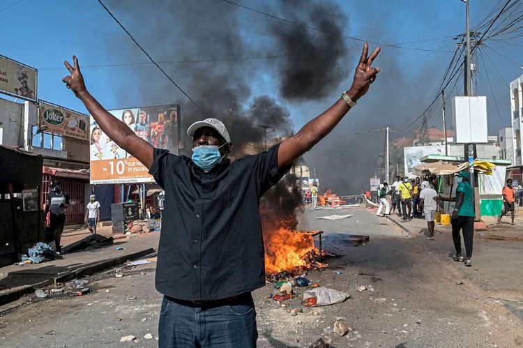 Demonstrant in Dakar vor einer brennenden Barrikade.