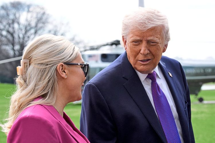 Zwei Personen unterhalten sich im Freien auf der South Lawn des Weißen Hauses. Im Hintergrund steht ein Hubschrauber, und die Szene spielt bei Tageslicht.