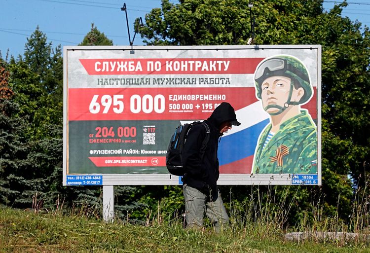 Ein Mann in St. Petersburg vor einem Plakat, das für den Einsatz im Krieg gegen die Ukraine wirbt.