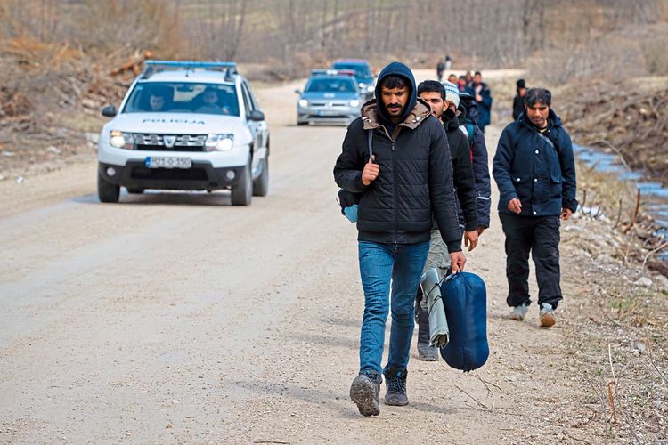 Flüchtlinge in Bosnien-Herzegowina bei Lipa gehen die Straße entlang.