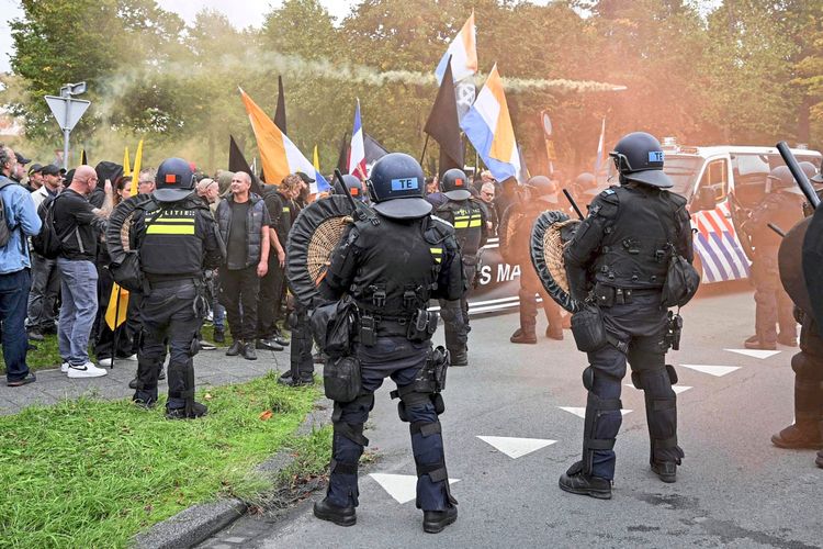 Niederländische Polizisten in Schutzausrüstung stehen Demonstranten während einer rechtsextremen Kundgebung unter dem Motto 
