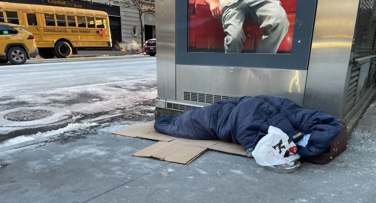 Person schläft mit Schlafsack auf der Straße